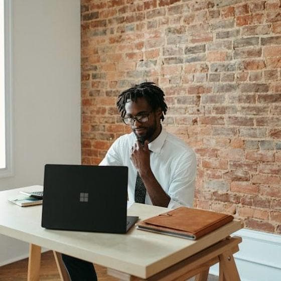 Ondernemer aan een bureau bij een bakstenen muur